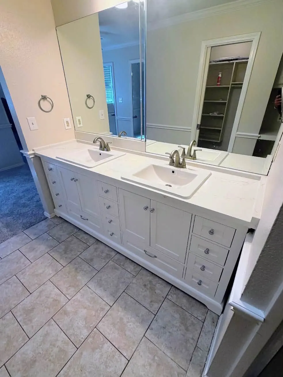 Remodeled bathroom with a white double vanity, quartz-look countertop, brushed nickel faucets, and tile floor