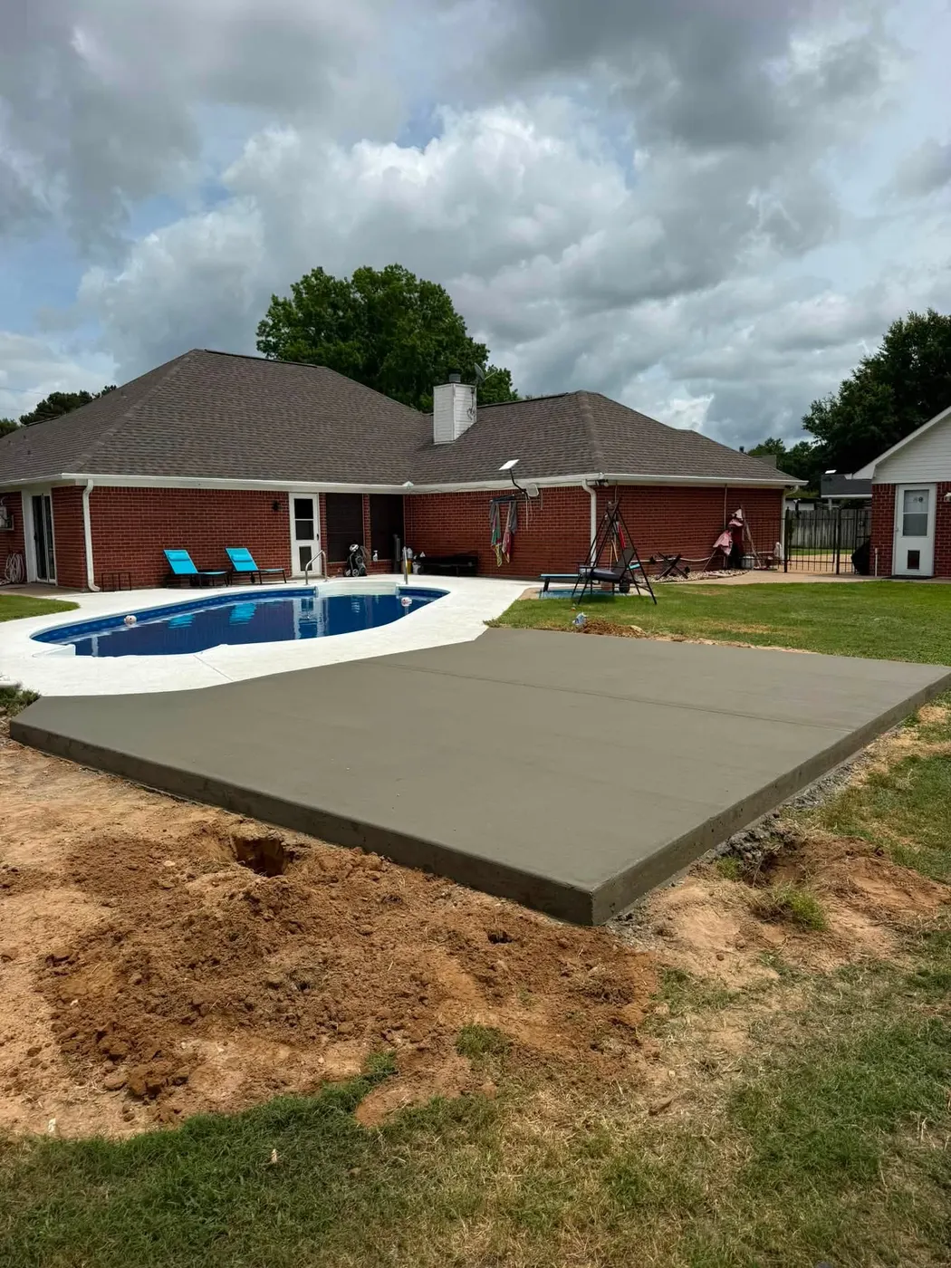 Freshly poured concrete slab beside a pool, ready for an outdoor structure