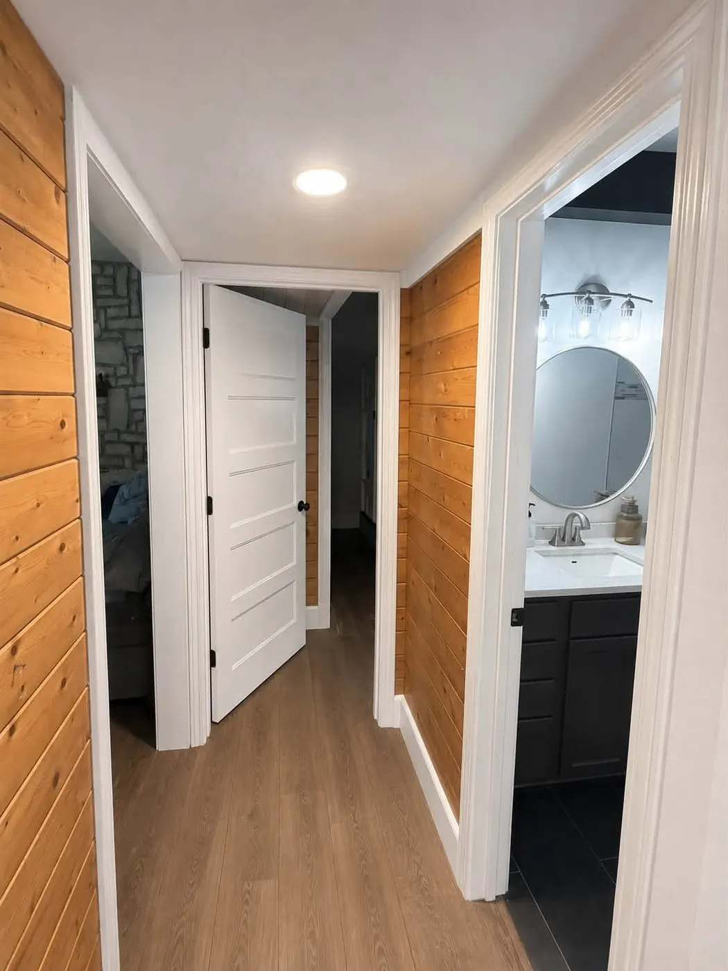 Hallway with pine shiplap walls, white five-panel doors, and plank floors