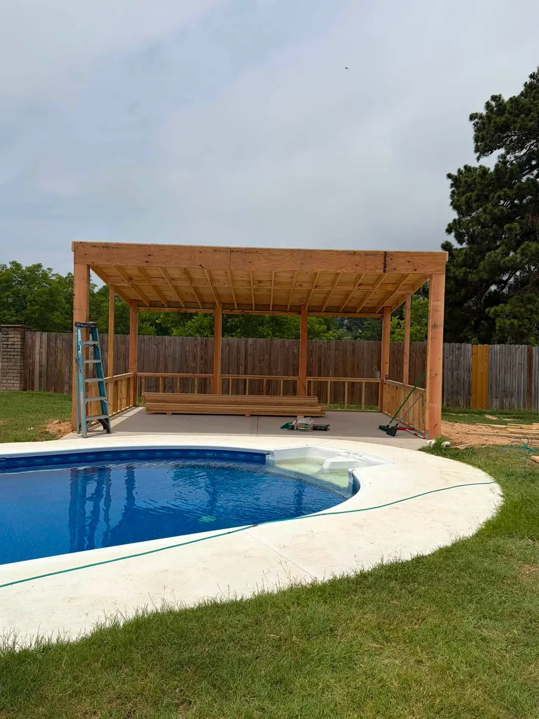 Wood pool pavilion being framed next to an in-ground pool